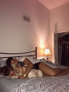 a woman laying on top of a bed next to a dog