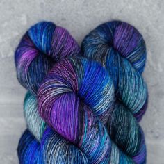 two skeins of blue and purple yarn sitting on top of eachother