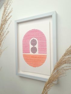 a white frame with an orange and pink design on it next to some dry grass