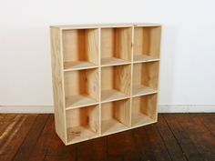 a wooden shelf with six compartments on the bottom and one section open to show wood flooring