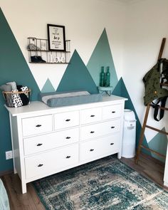 a baby crib with mountains painted on the wall behind it and a rug in front of it