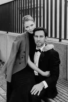 a man and woman are sitting on a bench posing for a black and white photo