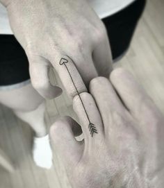 two hands holding each other with arrows tattooed on their thumbnails and finger tattoos