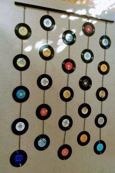 a wall hanging made out of old records with chains attached to it and various colored discs on the chain