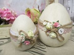 two decorated eggs sitting next to each other on top of a cloth covered tablecloth