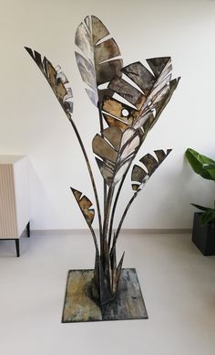 a metal sculpture with leaves on it in a room