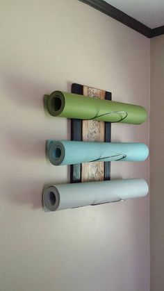 three yoga mats are hanging on the wall next to each other, with one rolled up