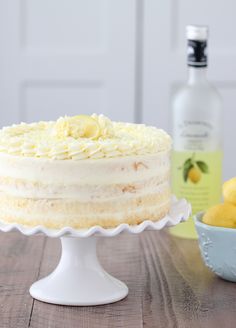 a cake sitting on top of a wooden table next to a bowl of lemons