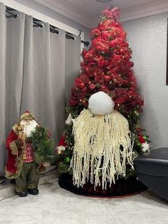 a christmas tree decorated with red and white decorations next to a small gnome figurine