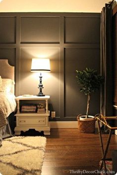 an image of a bedroom with gray walls and white furniture, including a lamp on the end table