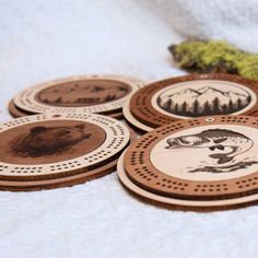 four wooden coasters with pictures of people and trees on them, sitting on a white surface