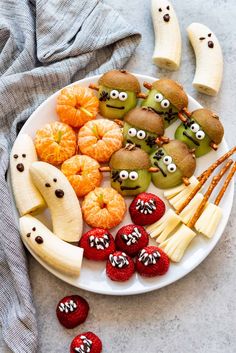 a white plate topped with apples, oranges and other fruit covered in googly eyes