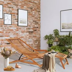 a wooden chaise lounge chair sitting in front of a brick wall with potted plants