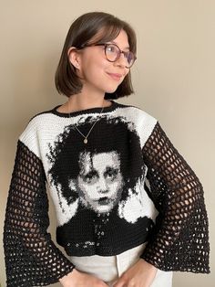 a woman wearing glasses and a knitted sweater with an image of a man on it