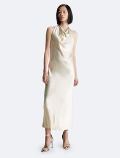 Featuring a lustrous glow, this maxi dress embodies effortless elegance. Cut in a sleeveless silhouette with a gentle drape at the halter neckline. Designed with a zip closure at the back.  Material: 73% Ethyl Vinyl Acetate, 27% Polyester. Chic Cream Halter Neck Dress, Cream Fitted Halter Neck Dress, Luxury Halter Neck Bias Cut Maxi Dress, Luxury Bias Cut Halter Maxi Dress, Elegant Calvin Klein Sleeveless V-neck Dress, Calvin Klein Woman, Effortless Elegance, Halter Neckline, Dress Clothes For Women