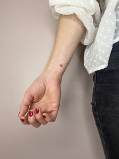 a woman's hand with a small tattoo on it, holding onto her left arm