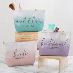 three bridesmaid makeup bags sitting on top of a wooden stool next to each other