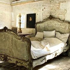 an old fashioned bed with white sheets and pillows in a room that has exposed brick walls