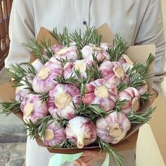 a man holding a bouquet of garlic and rosemary