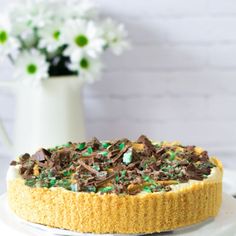 a cake sitting on top of a white plate next to a vase filled with flowers