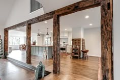 a large open concept kitchen and living room with hardwood floors, white walls, and wooden beams