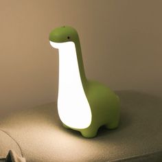 a green dinosaur lamp sitting on top of a cushion