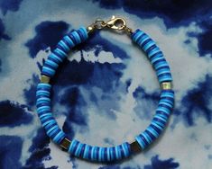 a blue and gold bracelet on a tie dye background