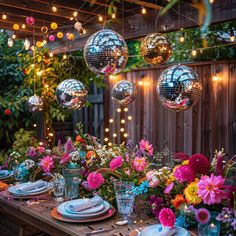 a wooden table topped with plates and vases filled with flowers next to disco ball lights