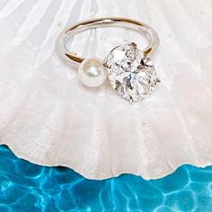 a close up of a ring with a pearl on it and water in the background