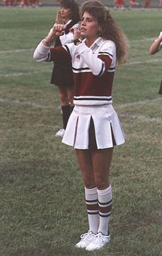 a girl in a cheerleader uniform holding a microphone