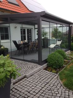 a house with glass walls and brick walkway