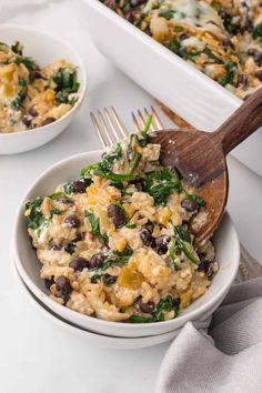 a white bowl filled with rice and black beans next to a wooden spoon on top of a table