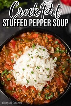 a bowl filled with chili and rice on top of a black table next to tomatoes