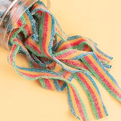 there is a cup with some colorful streamers in it on the table next to a pair of scissors