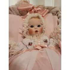 a baby doll sitting on top of a pink blanket