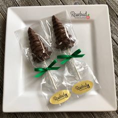 three chocolate candys wrapped in cellophane and tied with green ribbon on a white plate