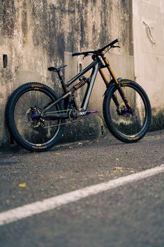 the bike is leaning against the wall on the side of the road with it's tire missing