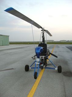 a small blue and white helicopter on an airport tarmac with yellow lines in the foreground