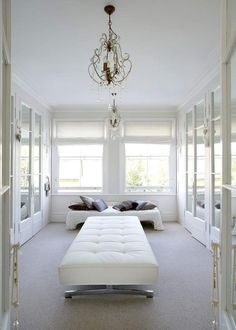 a room with white furniture and a chandelier hanging from it's ceiling