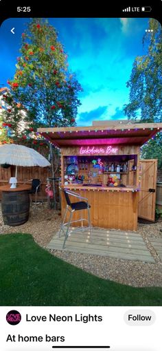 an outdoor bar with lights on it and some chairs in the grass next to it