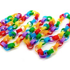 many different colored plastic bracelets on a white surface with one strand missing from the chain