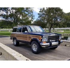 a brown and black jeep parked on the side of a road next to a lake