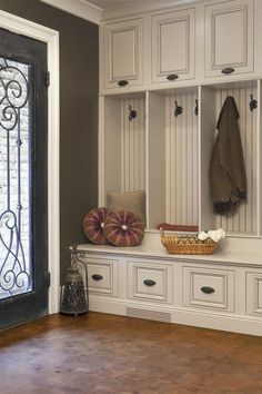 an entryway with white cabinets and drawers next to a glass door that has a coat rack on it