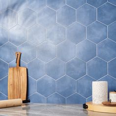 a blue tiled wall with wooden cutting board and rolling pin on the counter next to it