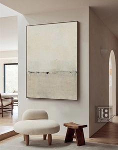 a living room with white furniture and a large painting hanging on the wall above it