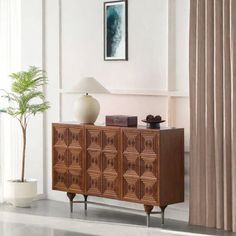 a living room with a large wooden cabinet next to a lamp and a potted plant