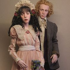 a man and woman dressed in period clothing standing next to each other with flowers on their head