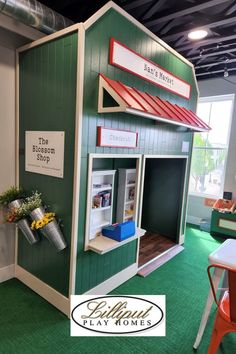 the play house is made out of wood and has a red roof, green walls, and white trim