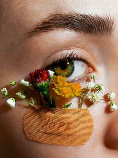 a woman with flowers on her eye and the word love spelled in front of her