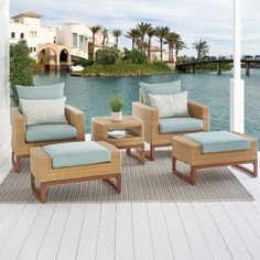 an outdoor living room with chairs and ottomans on a deck overlooking the water's edge